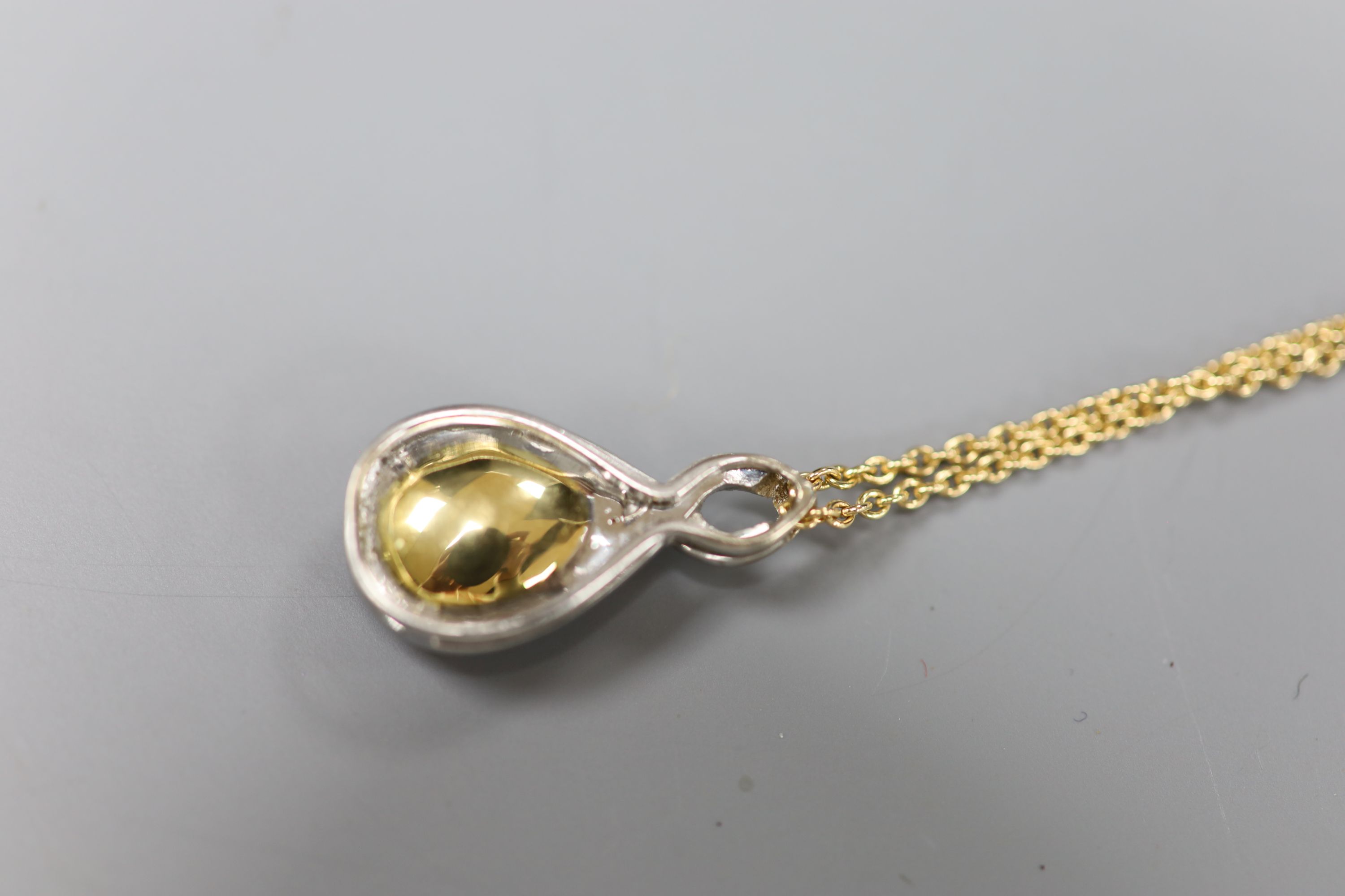 A white and yellow metal, garnet and diamond set teardrop shaped pendant, 29mm, on an 18k fine link chain,